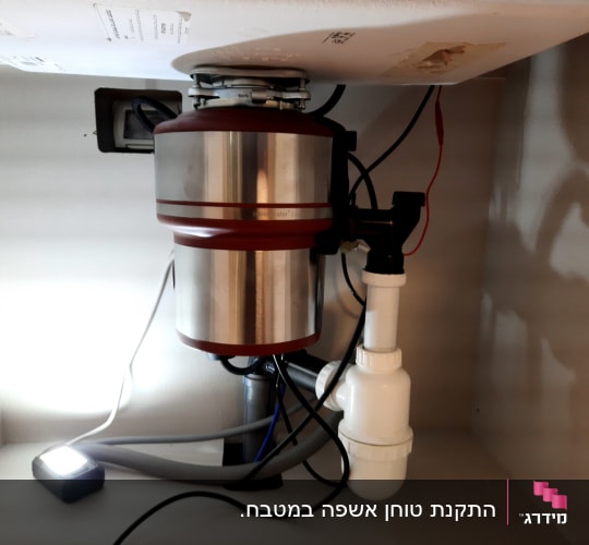 מתקן טוחן אשפה מתחת לכיור עם צינורות חיבור